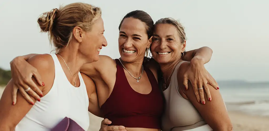 Three women hugging and laughing together.